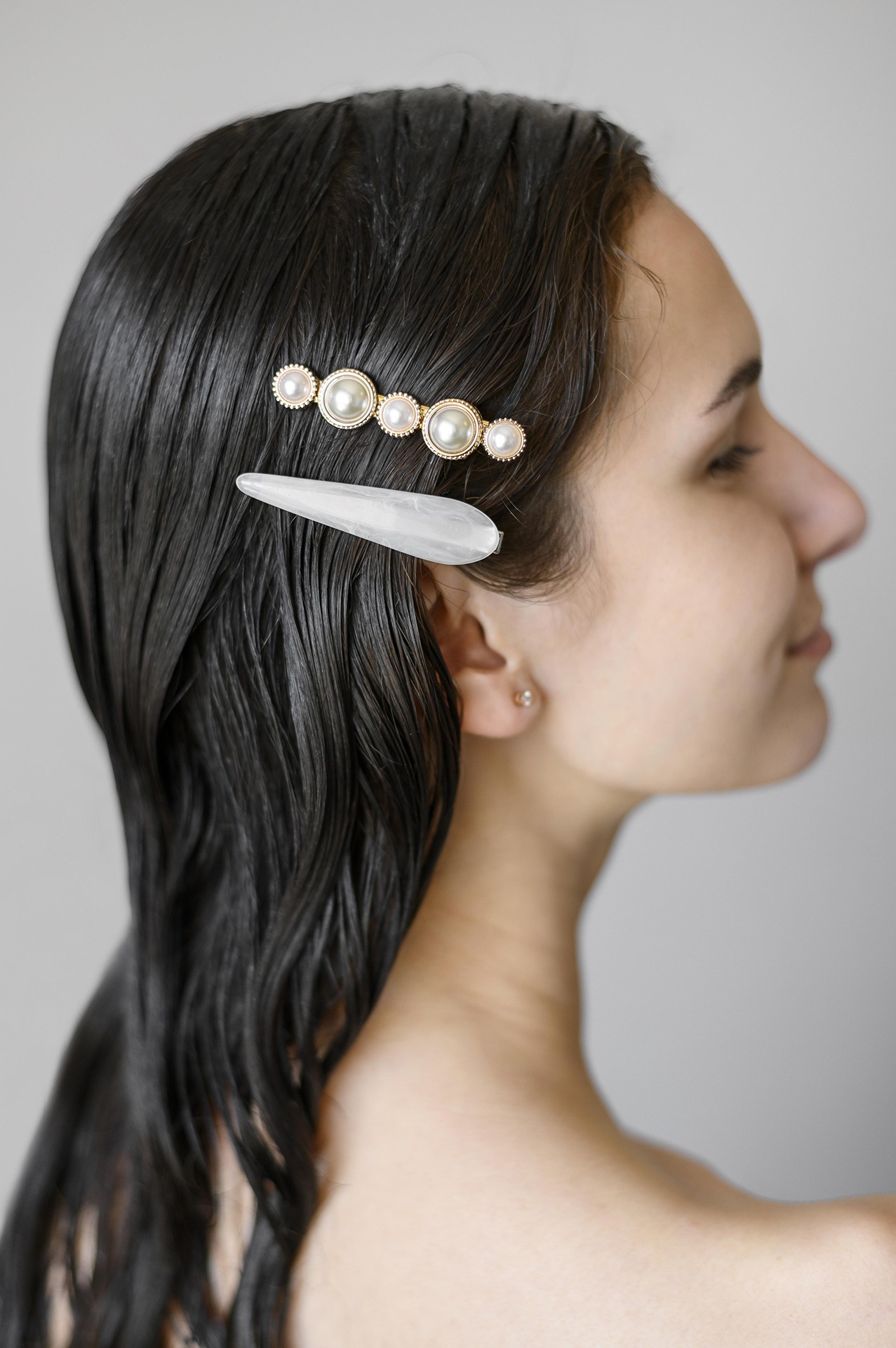 Woman wearing two hair clips is looking to the left.