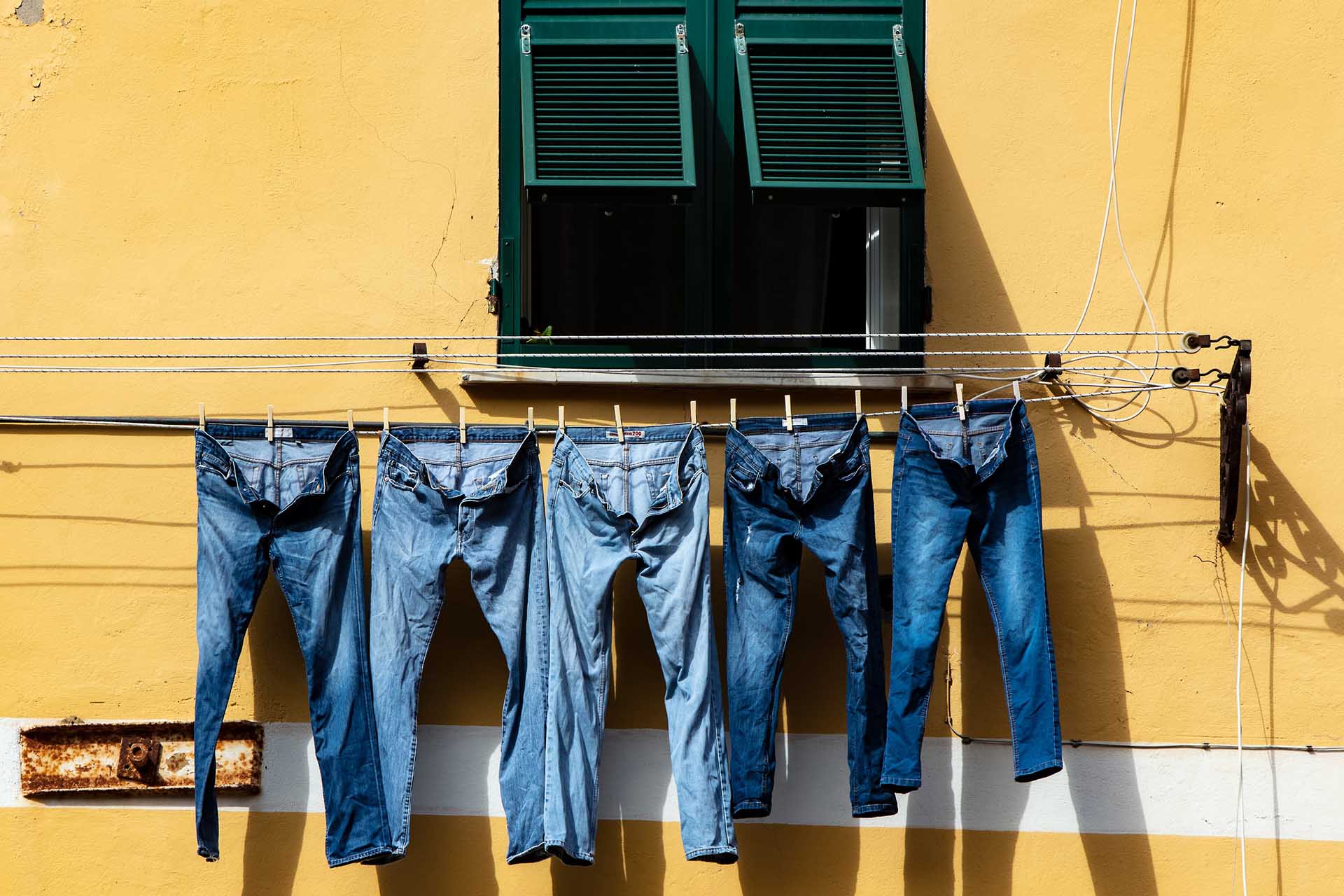 Jeans hanging from a string outside a window.