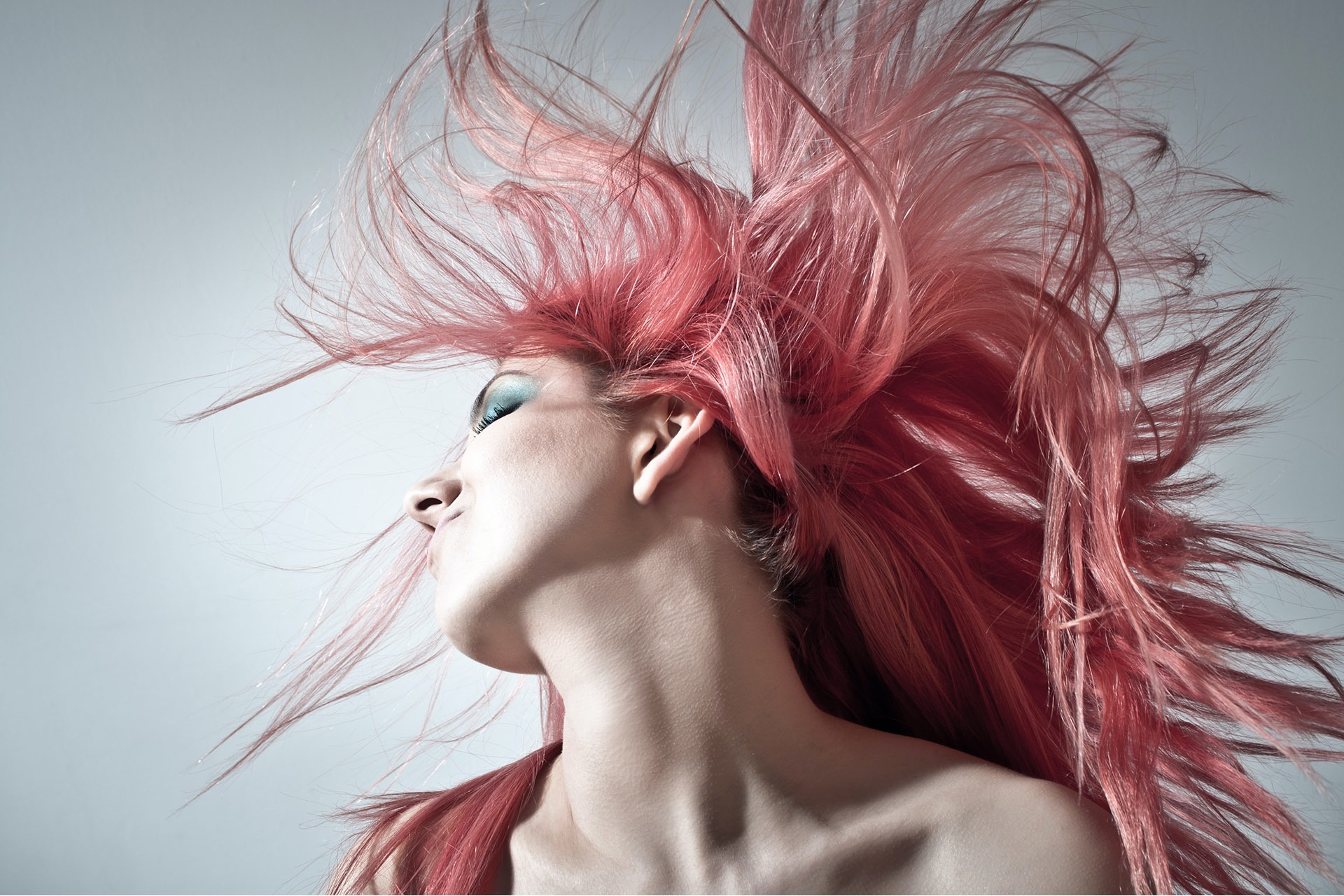 Woman with long pink hair rocks her head to the side. 