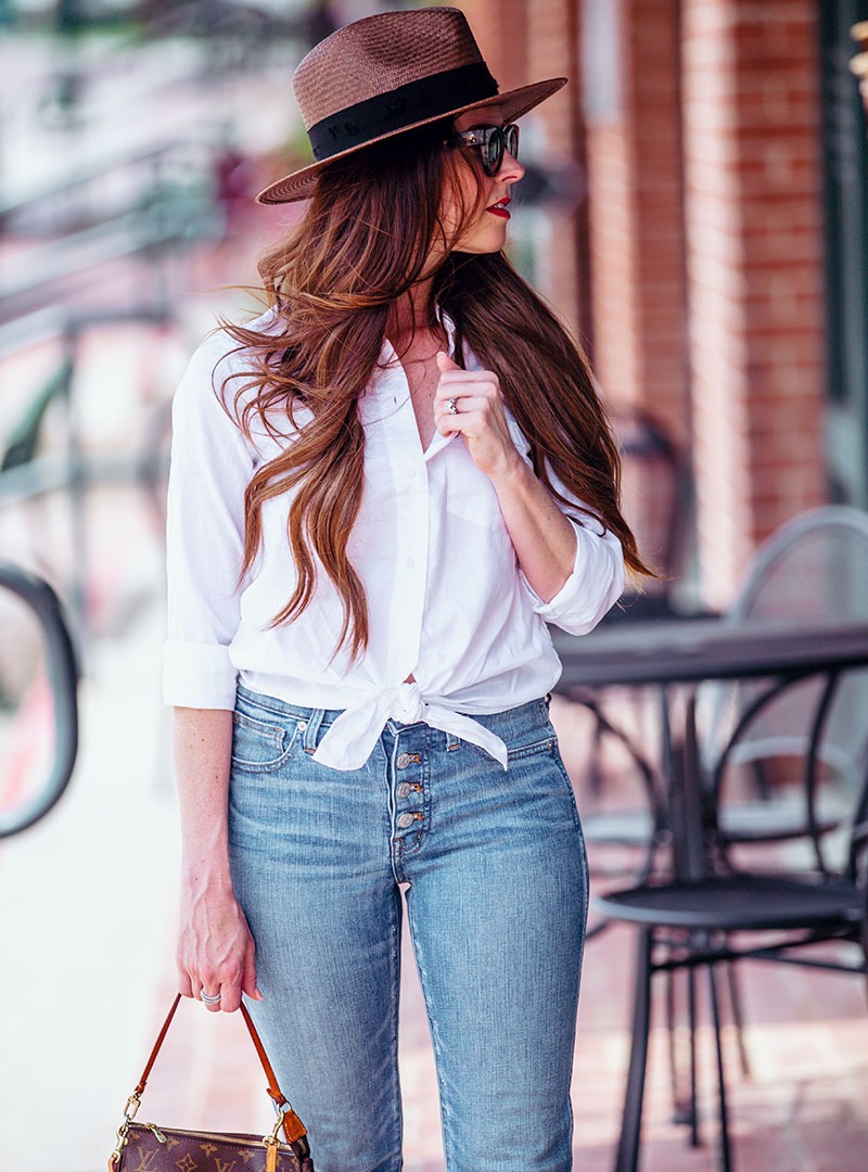A woman with a blue denim pants and a white shirt on the street.