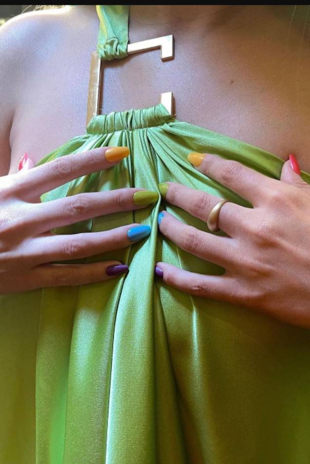 Woman's hands with polished nails in cyan color offering a seashell
